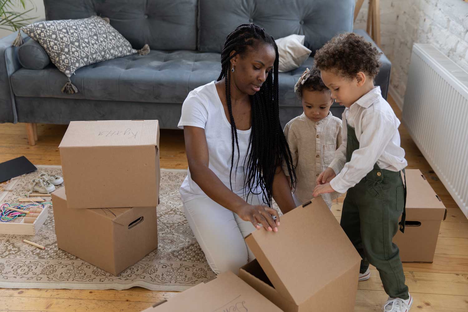 Woman with children on their new home unpacking boxes
